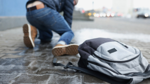 Backpack lying on slippery paving slabs near falling man, slip and fall accident