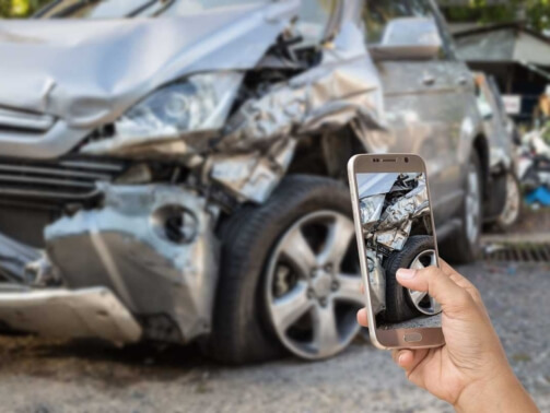 Hand of woman holding smartphone and take photo of car accident